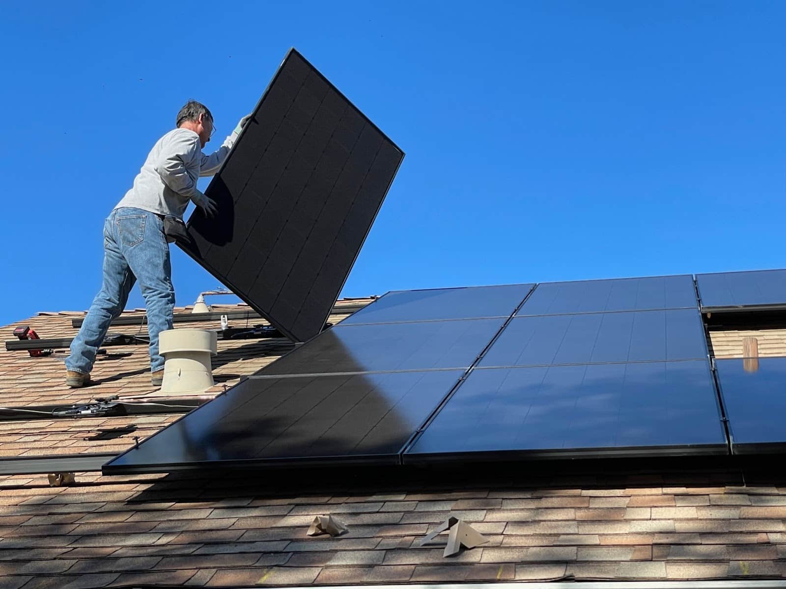 A roofing worker installs solar panels on a roof