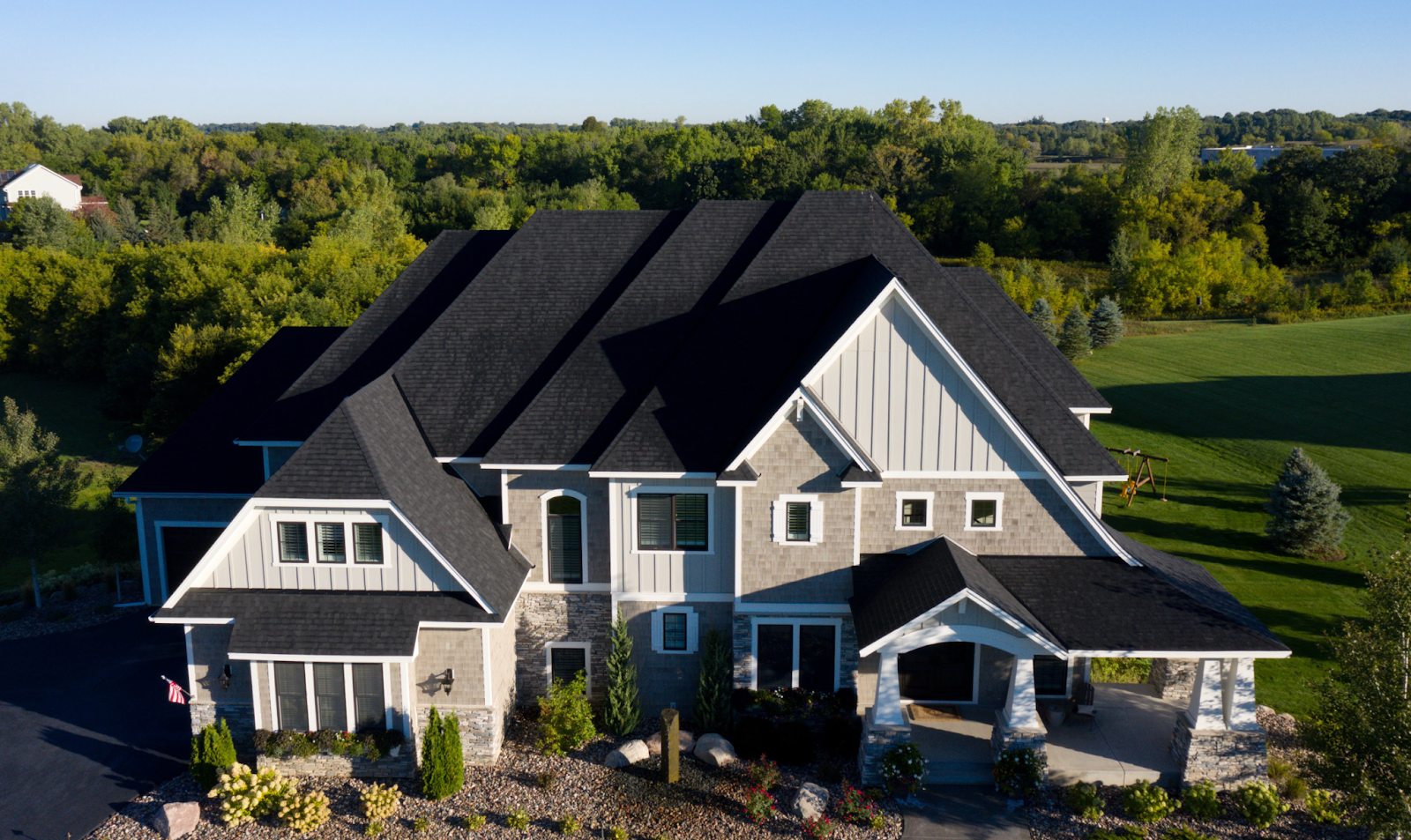 Very large home with various stone sections that has had a new black shingle roof installed