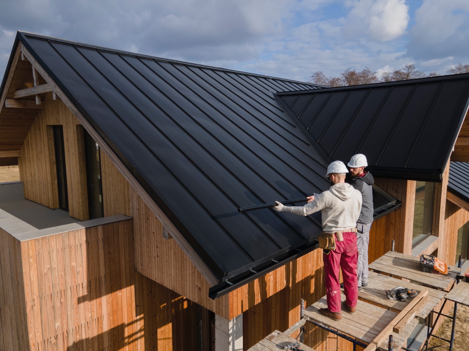 Two roofers installing a black metal roof