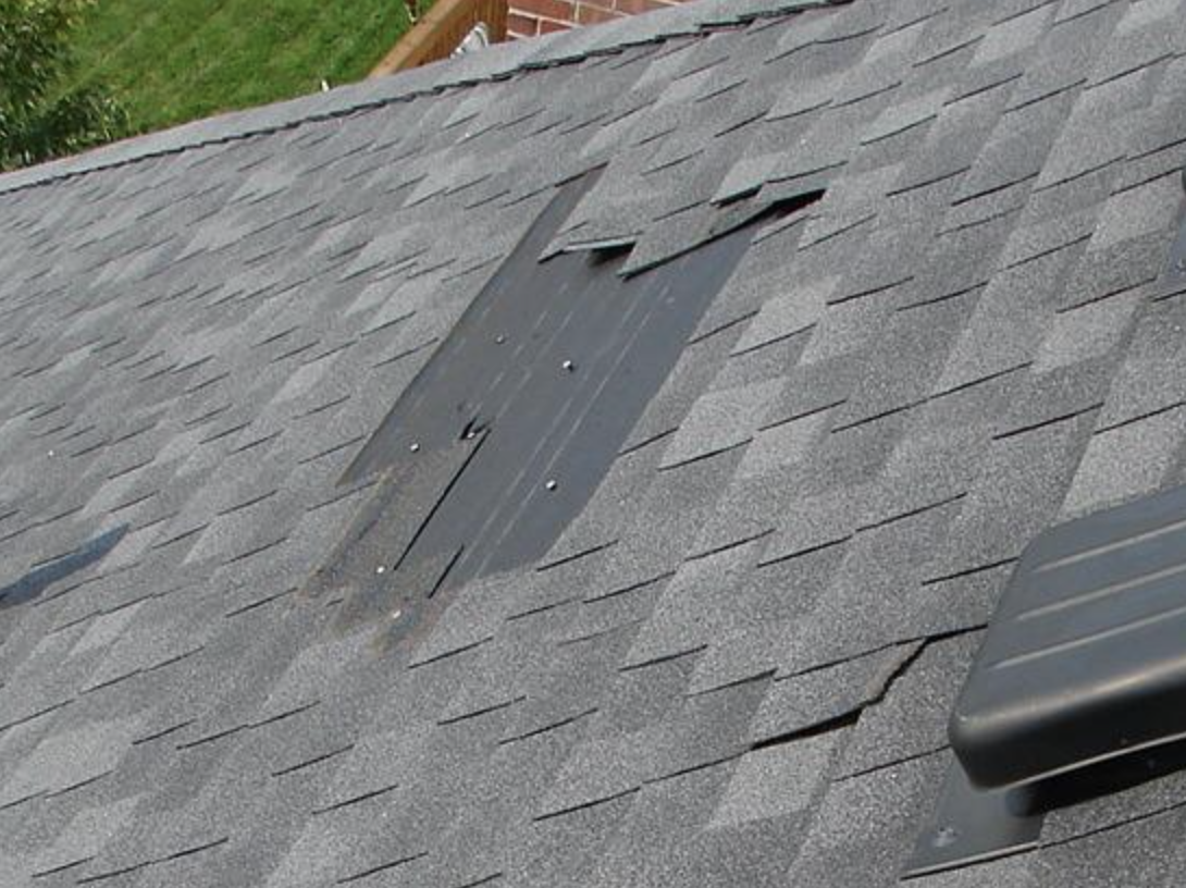 A section of shingles on a roof that has been damaged by weather