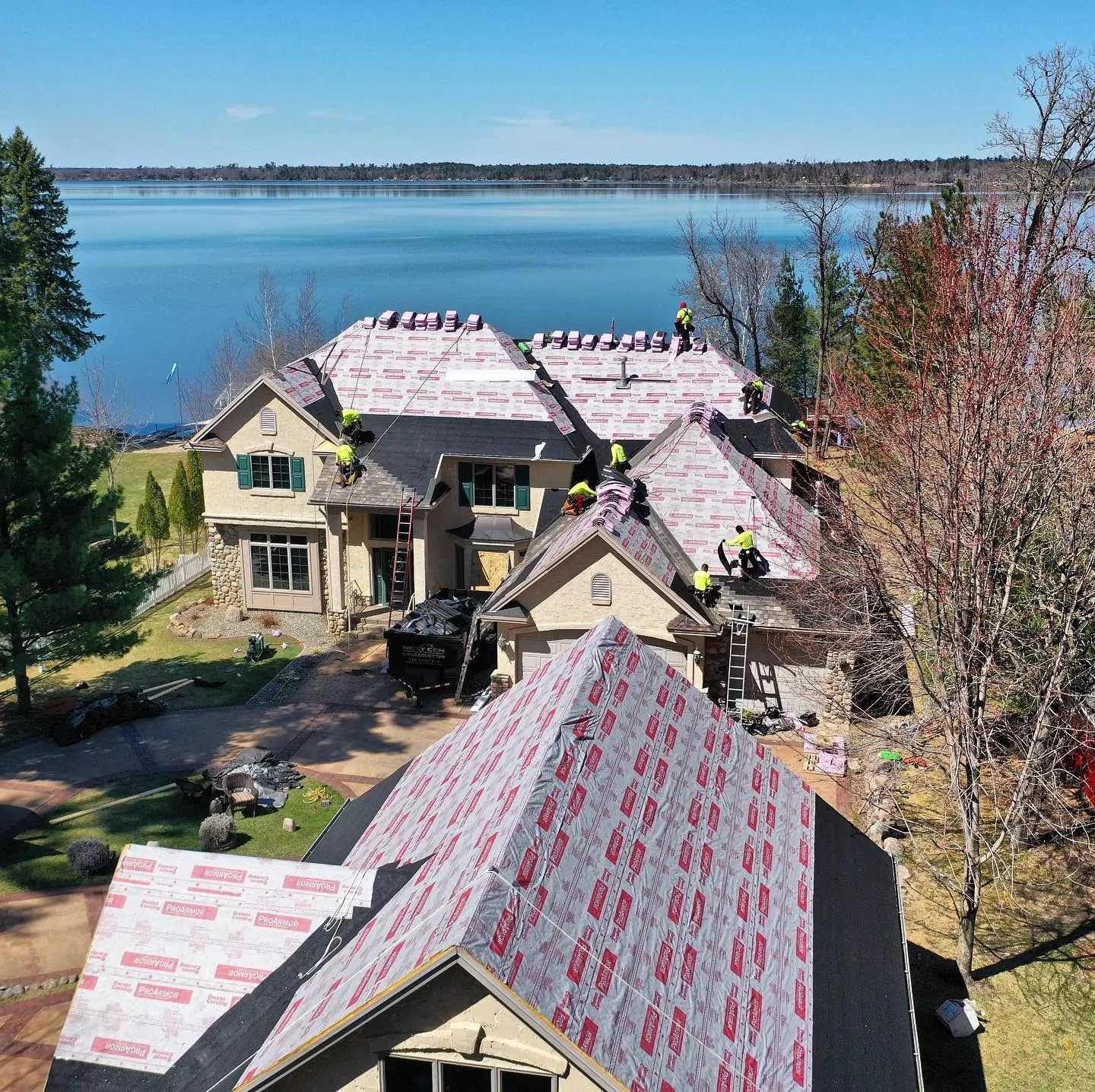 Roofers working simultaneously to replace two nearby buildings' roofs at once