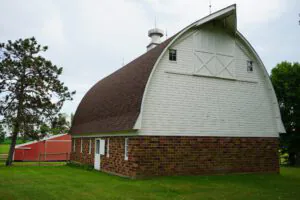 Large white siding and brick barn seen on a cloudy day