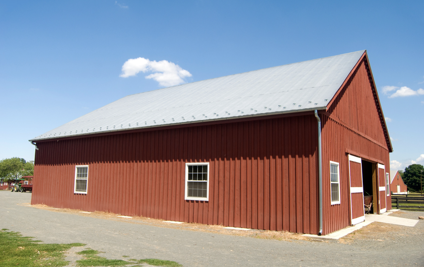 Red barn with a newly installed white rooftop
