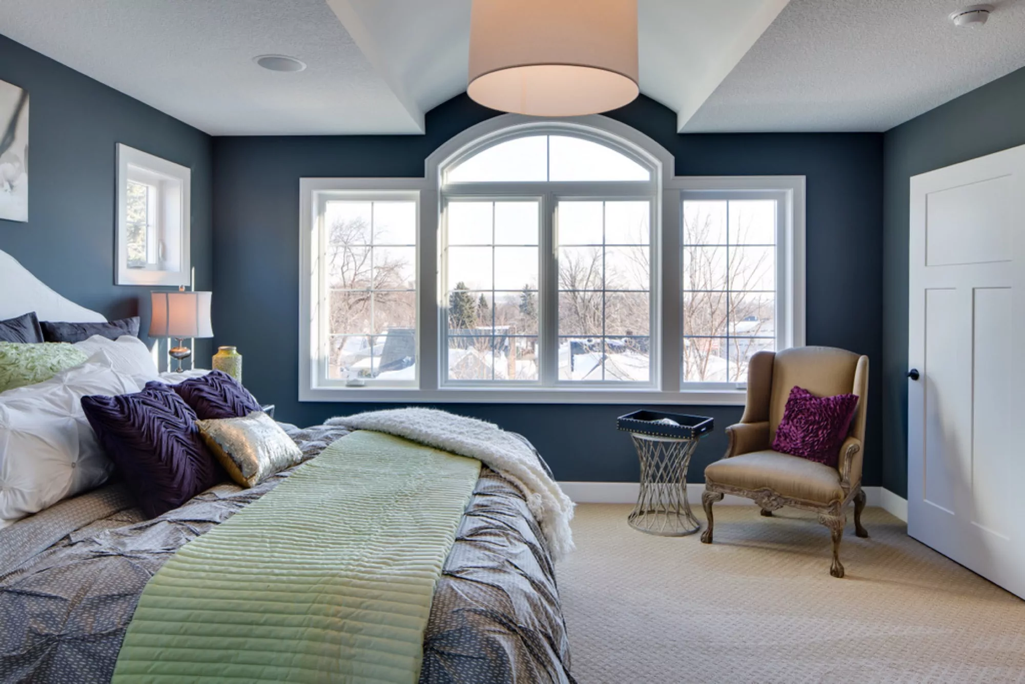Large master bedroom with a wide window on its wall