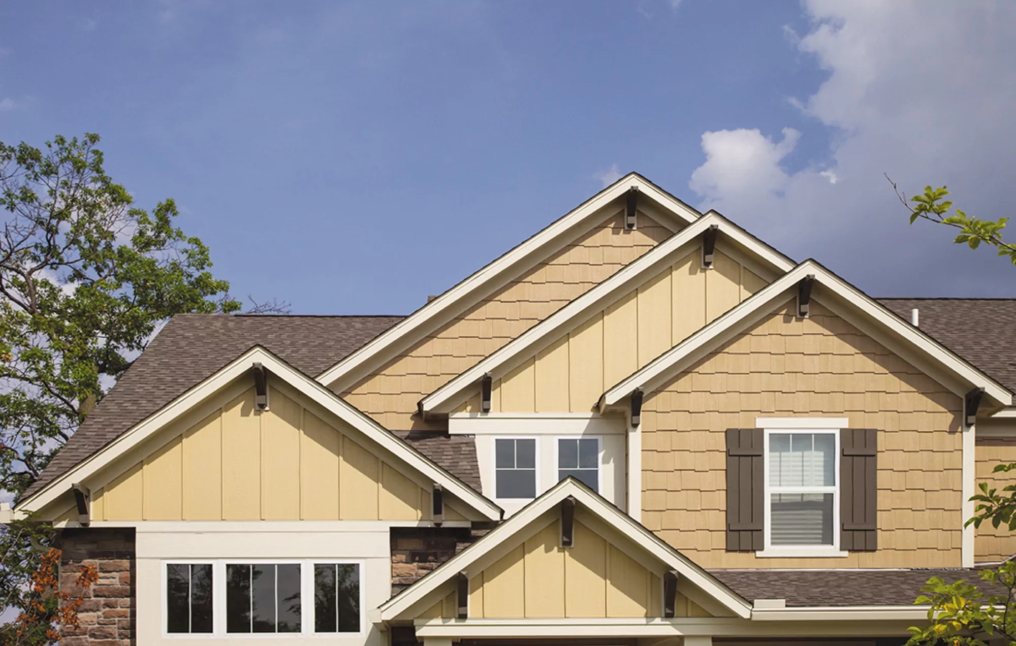 Curbside view of a yellow home with asphalt shingle roofing