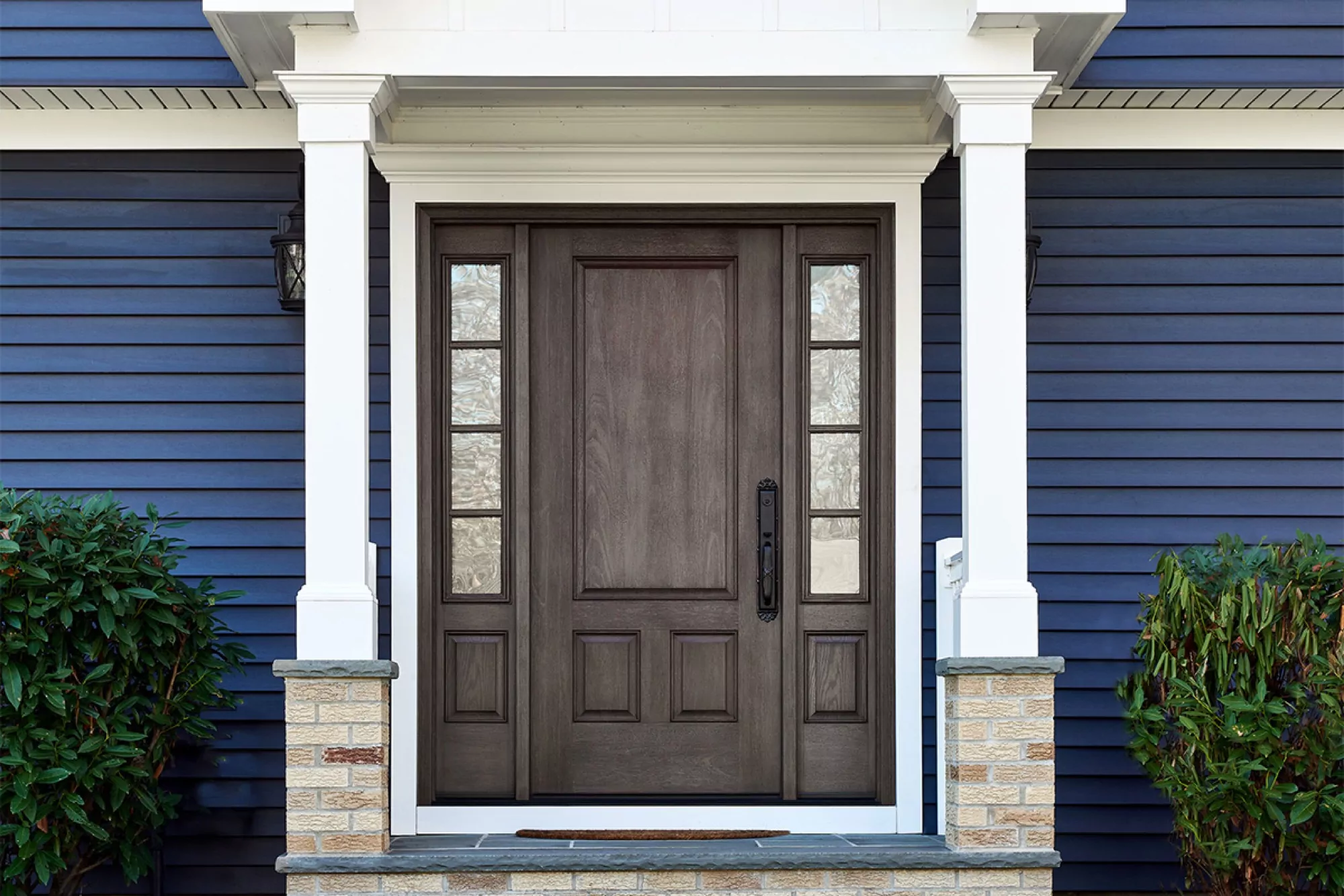 Dark wood entryway door on a blue home