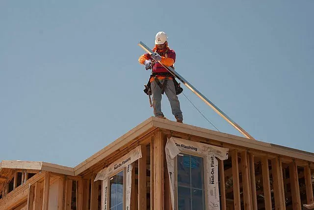 Roofer dealing with a board atop a roof