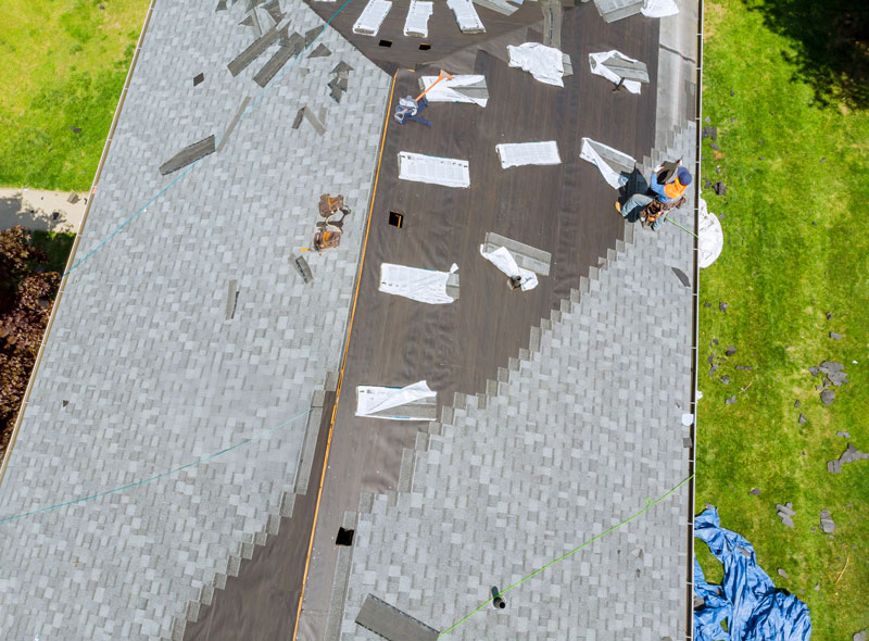 roofer working on replacement asphalt shingle roof